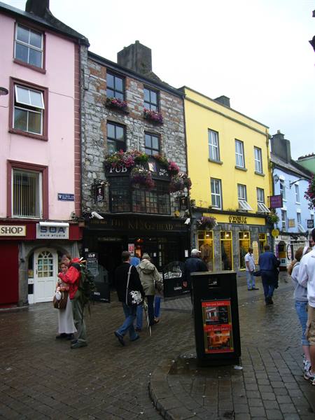 Pedestrians outside The King's Head pub among colorful facades in Galway