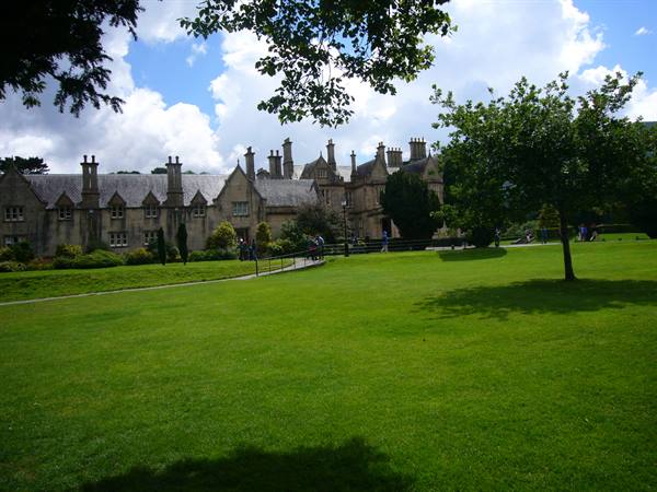 Muckross House, gardens with green lawn and visitors under a cloudy sky
