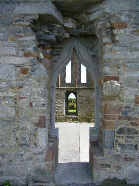 Gothic stone doorway of ruined abbey walls, daylight beyond