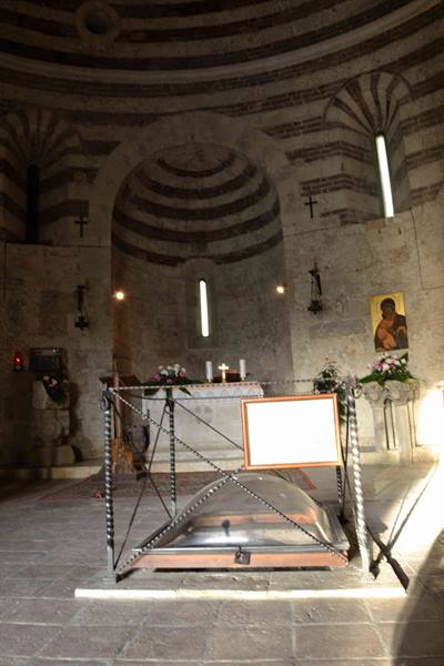 Stone altar and glass case inside a medieval striped-brick church