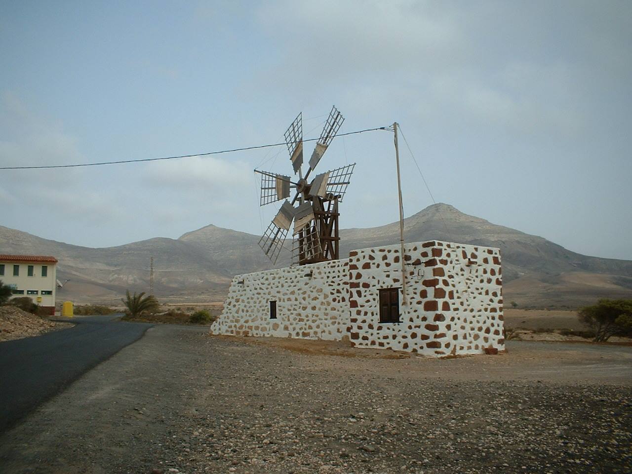 Old windmill with wooden blades on stone walls amid Fuerteventura's arid mountains