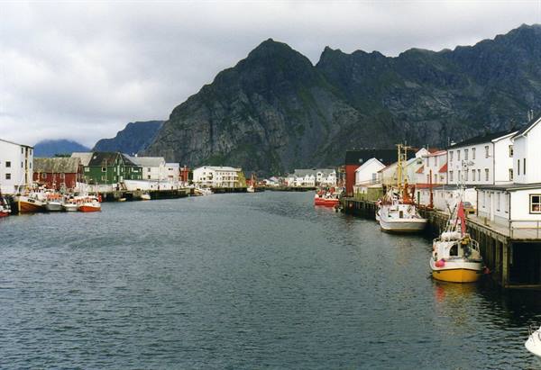 Henningsvær harbor, colorful wooden houses and fishing boats beneath grey mountains