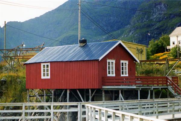 Red wooden stilt house by the harbor, mountains behind, Lofoten