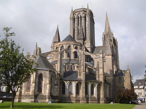 Coutances Cathedral: gothic stone spires and buttresses under cloudy sky