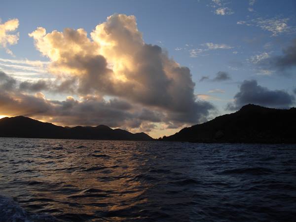 Sunlit clouds over the Virgin Islands, dark sea between the hills