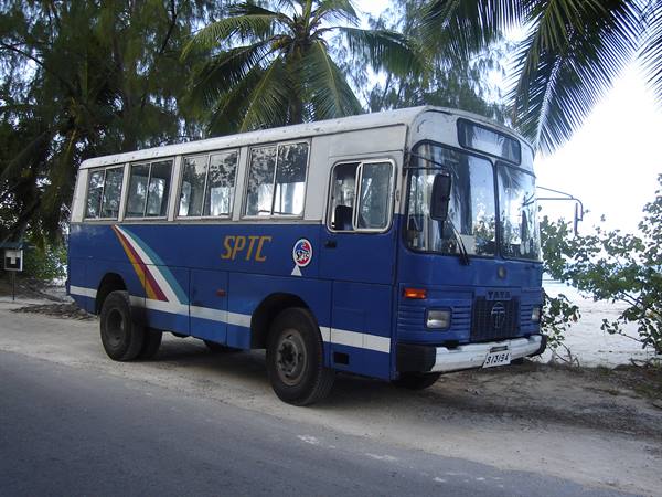 Old blue SPTC bus parked under palm trees, Seychelles