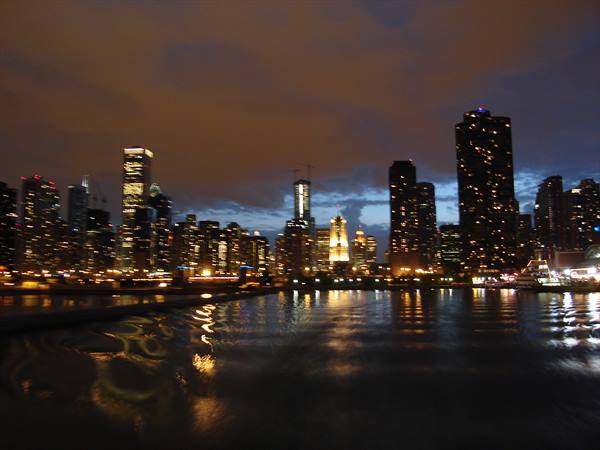 Illuminated Chicago skyscrapers reflecting on dark water at night