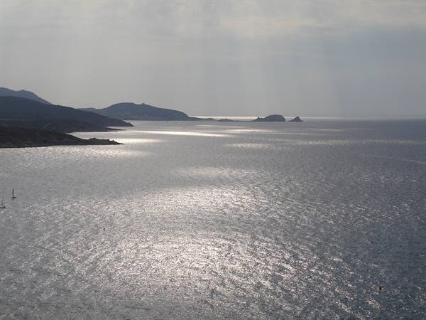 Silvery light on the sea before Capo Ferro hills, small boats anchored