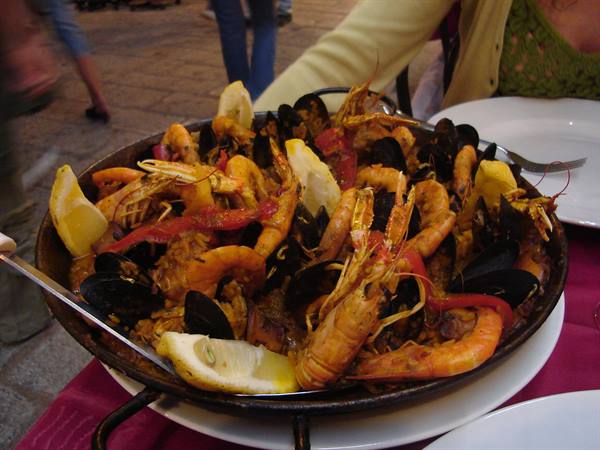 Seafood paella with prawns, mussels and lemon wedges in the black pan