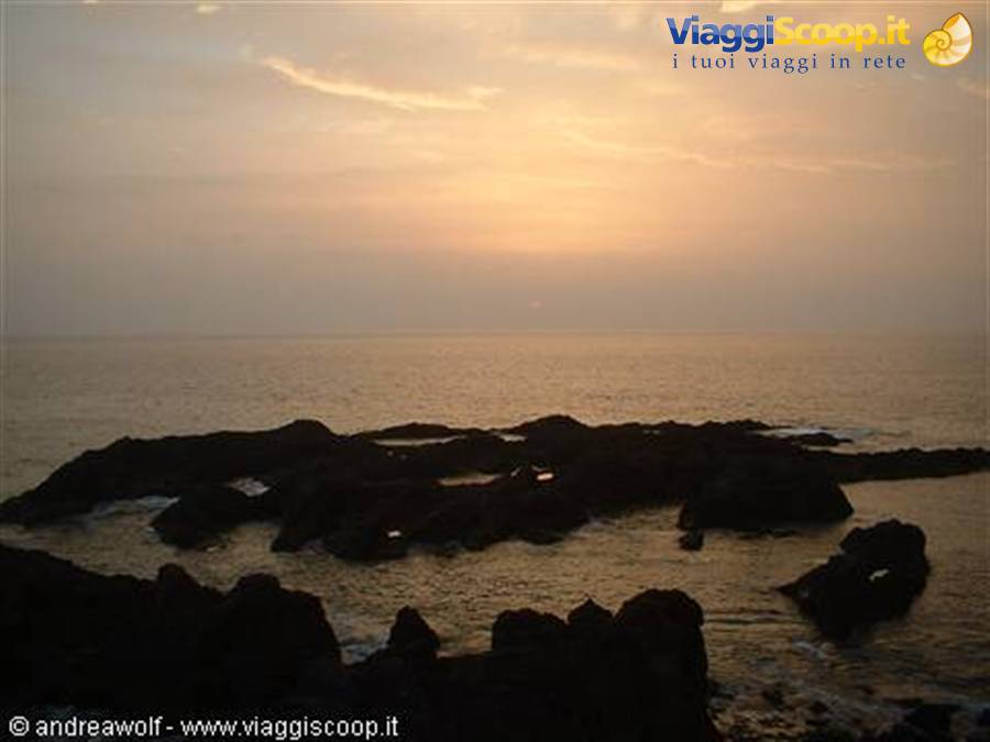 Dark rocks on the ocean under a golden dawn sky