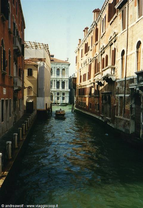 Venice canal with a boat gliding between old brick palaces in sunlight
