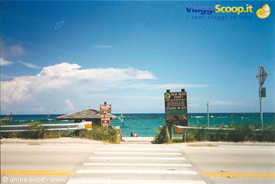 Crosswalk leading to the beach, green sign, turquoise sea under white clouds