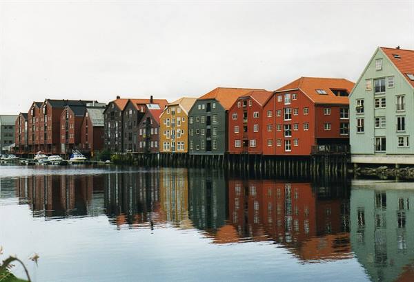 Colorful wooden warehouses on stilts reflected in the Nidelva river, Trondheim