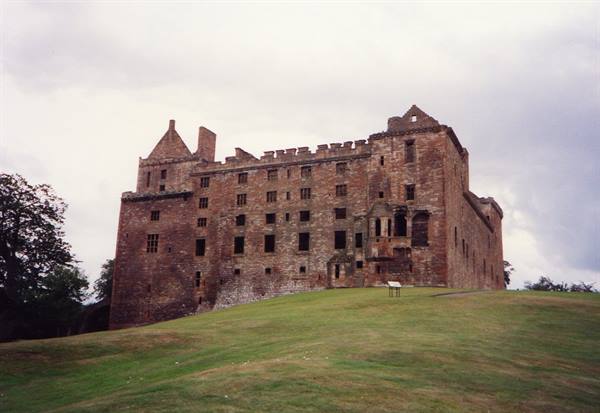 Linlithgow Palace, red stone ruins under cloudy sky, green lawn in front