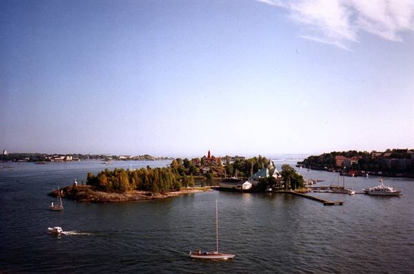 Tree-covered island with buildings among sailboats, Helsinki archipelago