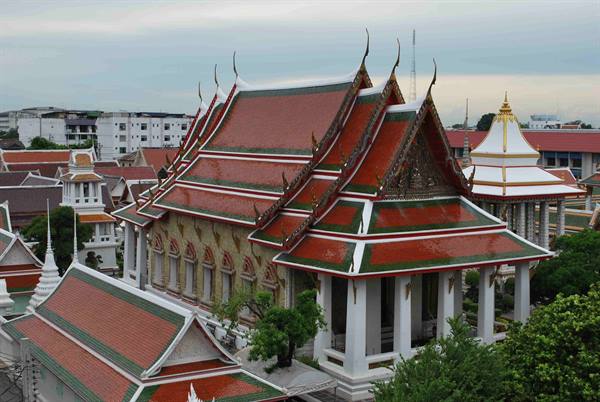 Red and green roofs of Wat Pho temple in Bangkok amid modern buildings
