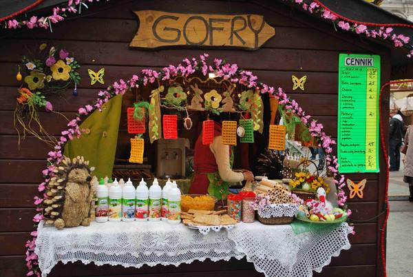 Wooden waffle stall with Gofry sign and price list, vendor serving decorated sweets