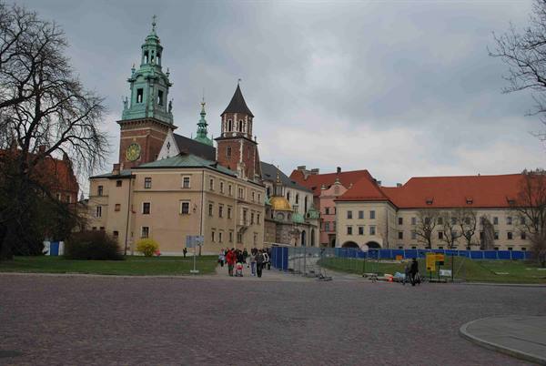 Wawel Cathedral in Kraków with green spire, tourists walk across the square