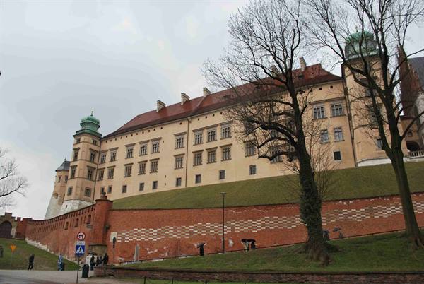 Wawel Castle in Kraków under a grey sky, red brick walls and bare trees