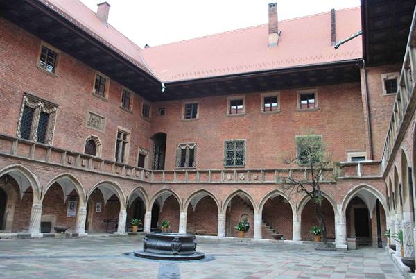 Brick courtyard with pointed Gothic arcades and central fountain, Collegium Maius Kraków