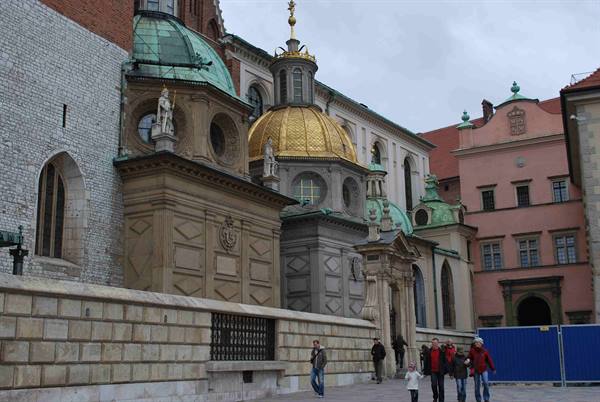 Golden and green domed chapels of Wawel Cathedral, visitors walking below