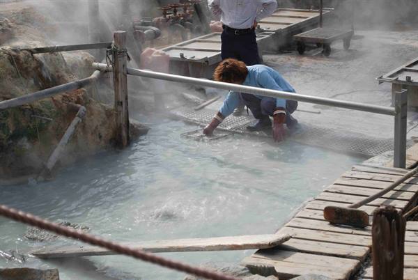Workers rake the steaming hot spring pool at Kusatsu