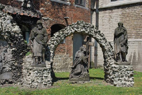 Stone statues with rough stone arch in a brick courtyard