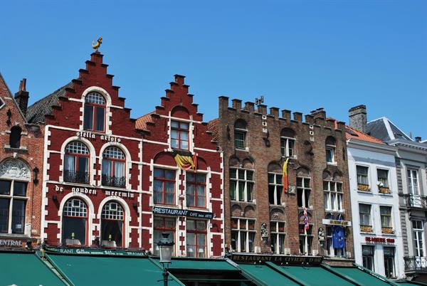 Stepped brick facades on the Markt in Bruges under a blue sky