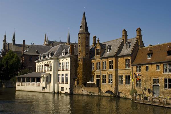 Brick houses and medieval tower along Bruges canal, golden light