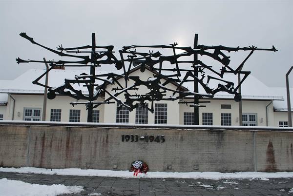 Metal memorial sculpture of intertwined bodies on the Dachau camp wall
