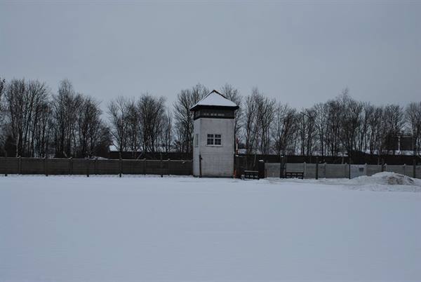 White wooden guard tower on snow, bare trees, grey sky, Dachau memorial