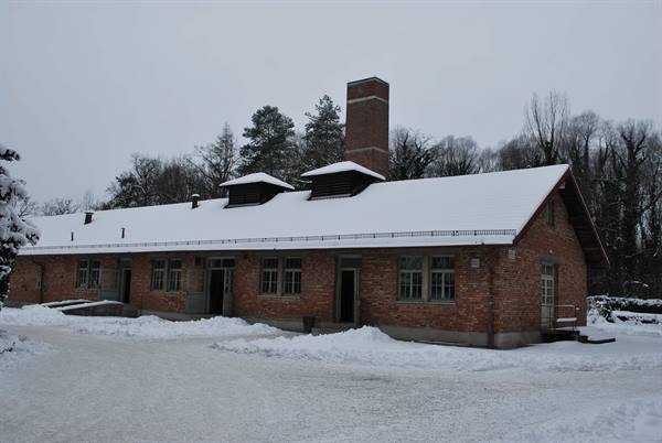 Dachau red-brick crematorium building under snow, gray winter sky