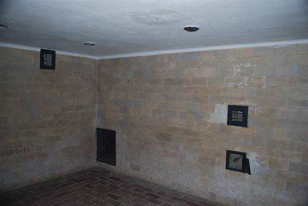 Empty room with stone block walls, iron grated vents and brick floor