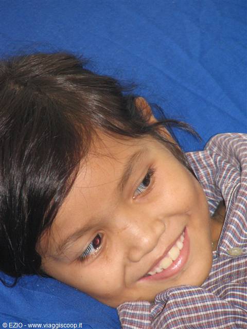 Smiling girl in checkered shirt lying on blue fabric
