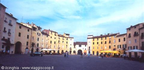 Piazza dell'Anfiteatro in Lucca, colorful buildings, umbrellas and people under blue sky