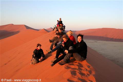 Tourists sitting on the crest of a red Sossusvlei sand dune
