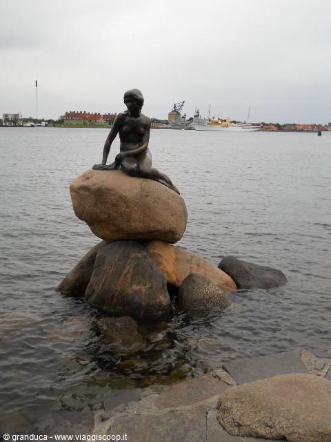Bronze Little Mermaid statue sitting on rocks by Copenhagen harbour