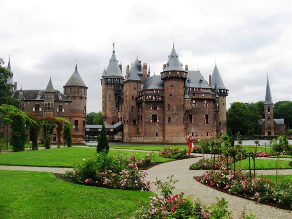 De Haar castle with brick towers among blooming gardens and green lawn