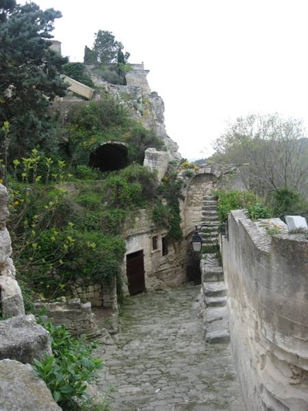 Medieval stone ruins with stairway and doorway, greenery covering the village