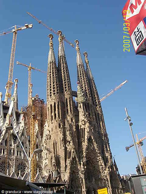 Sagrada Familia towers in Barcelona surrounded by construction cranes under blue sky