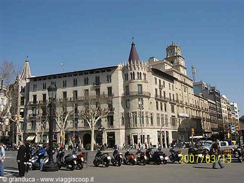 Stone neo-Gothic building with conical tower, scooters parked under blue sky
