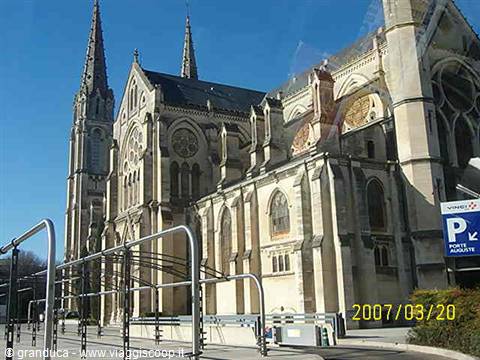 Gothic stone cathedral with spires and flying buttresses under blue sky