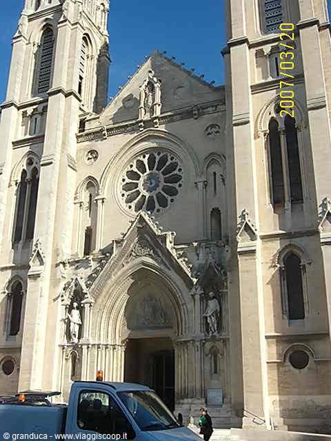 Gothic stone facade with rose window and statues, a van parked in front