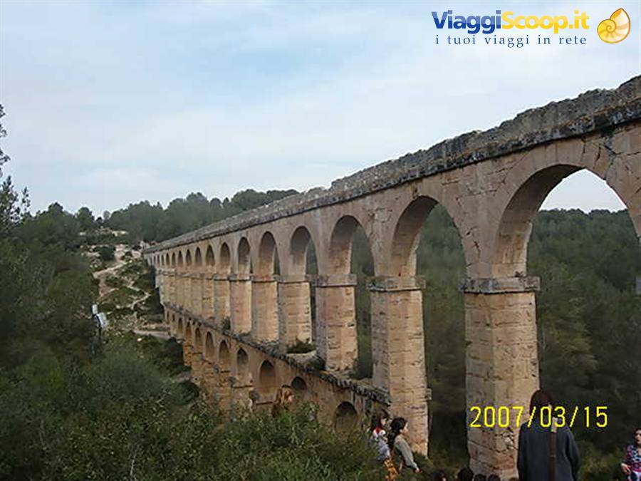 Roman aqueduct Les Ferreres, stone arches among trees with visitors