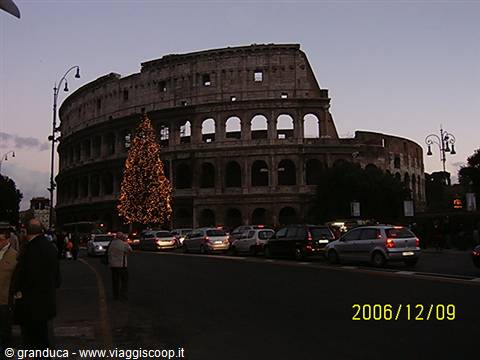 The Colosseum in Rome with a large lit Christmas tree at dusk