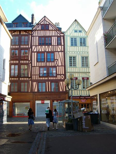 Colorful half-timbered houses in Rouen, pedestrians walking on cobbled street