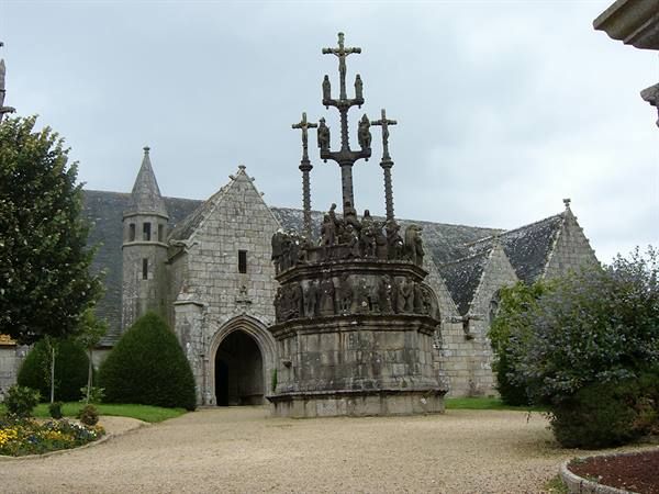 Granite calvary before a Breton parish church, overcast sky