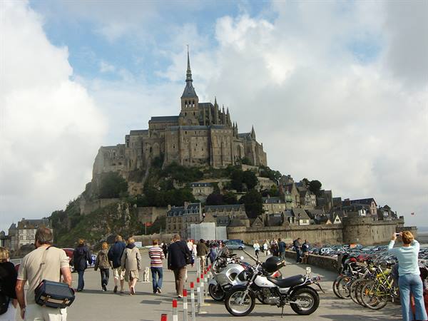 Tourists and motorbikes along the road leading to Mont Saint-Michel abbey