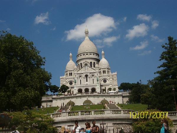 The white Sacré-Cœur basilica rises above the lawn under a blue sky
