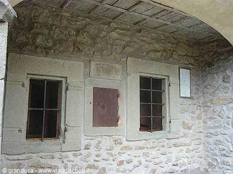Two barred windows on stone wall beneath wooden vault